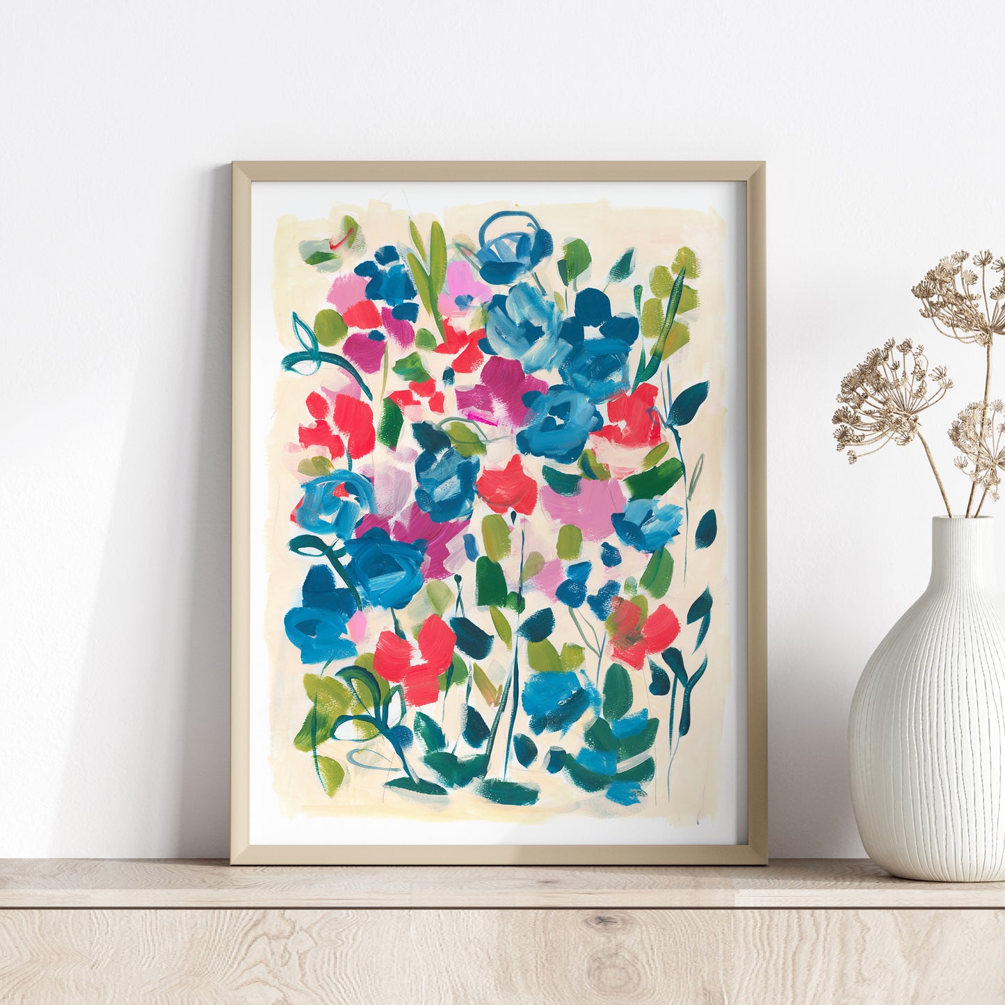 Red and blue abstract floral art print in wood frame against white wall