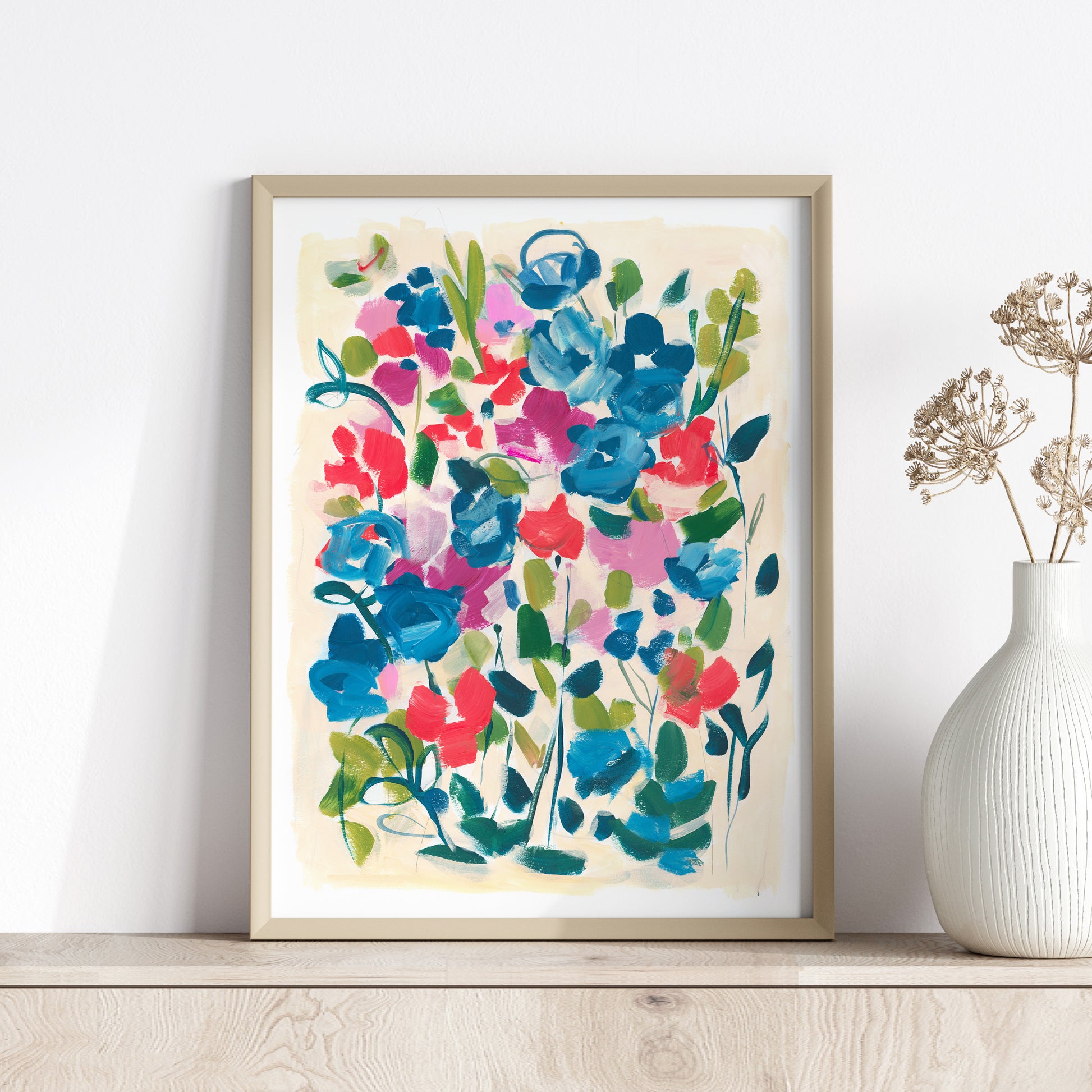 Red and blue abstract floral art print in wood frame against white wall