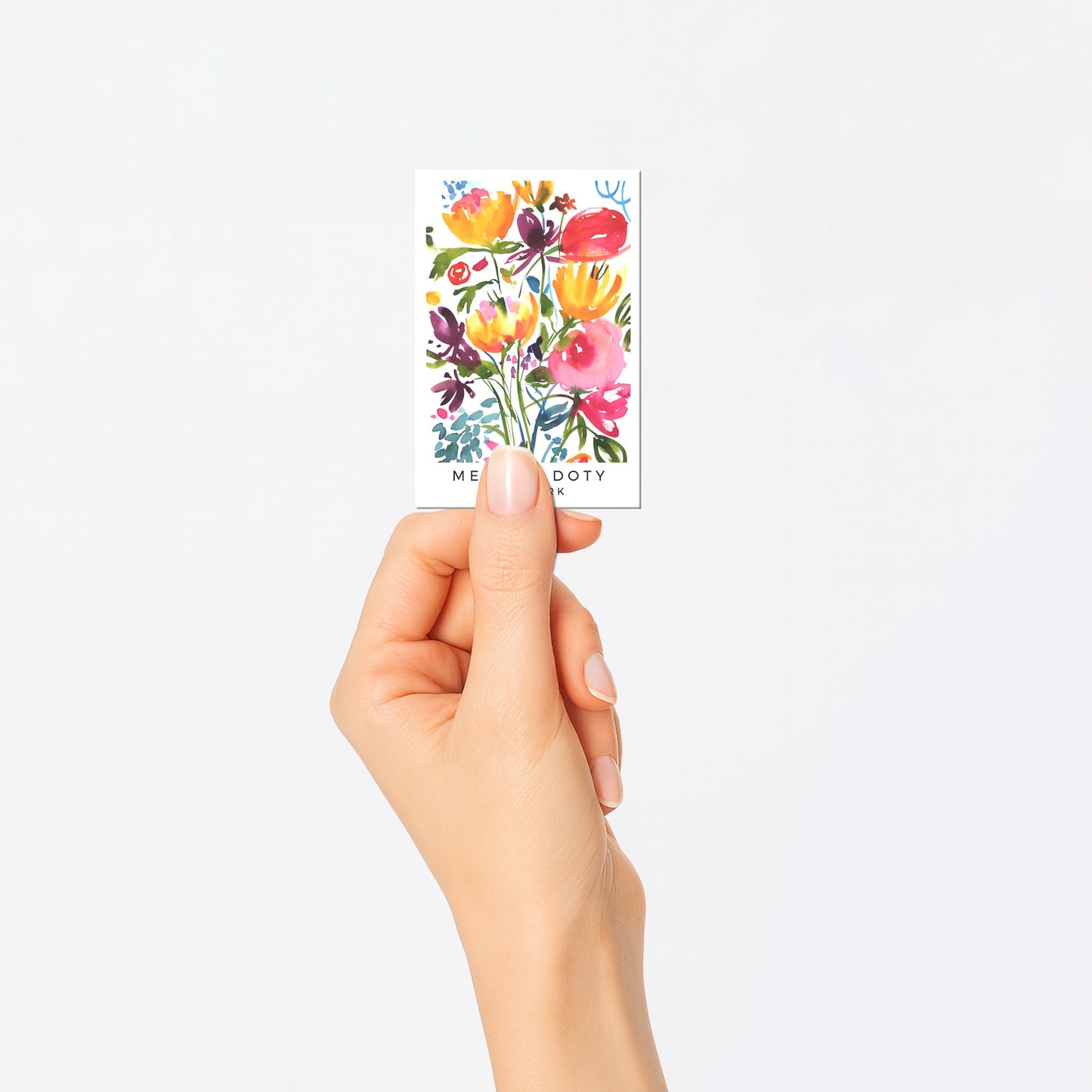 Hand holding a card with colorful floral design on a white background