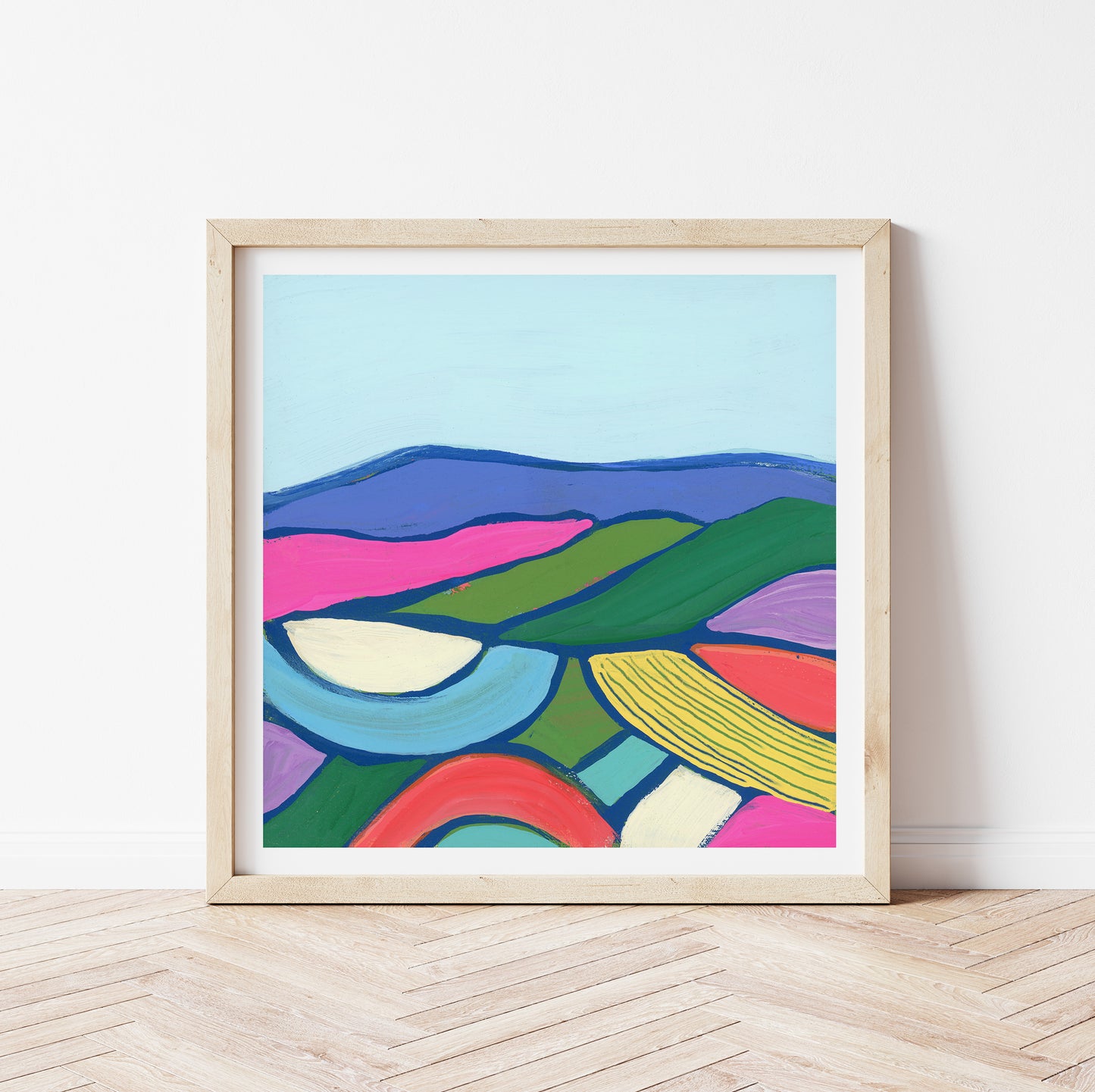 Framed abstract landscape artwork with colorful wavy patterned mountains on a white wall.