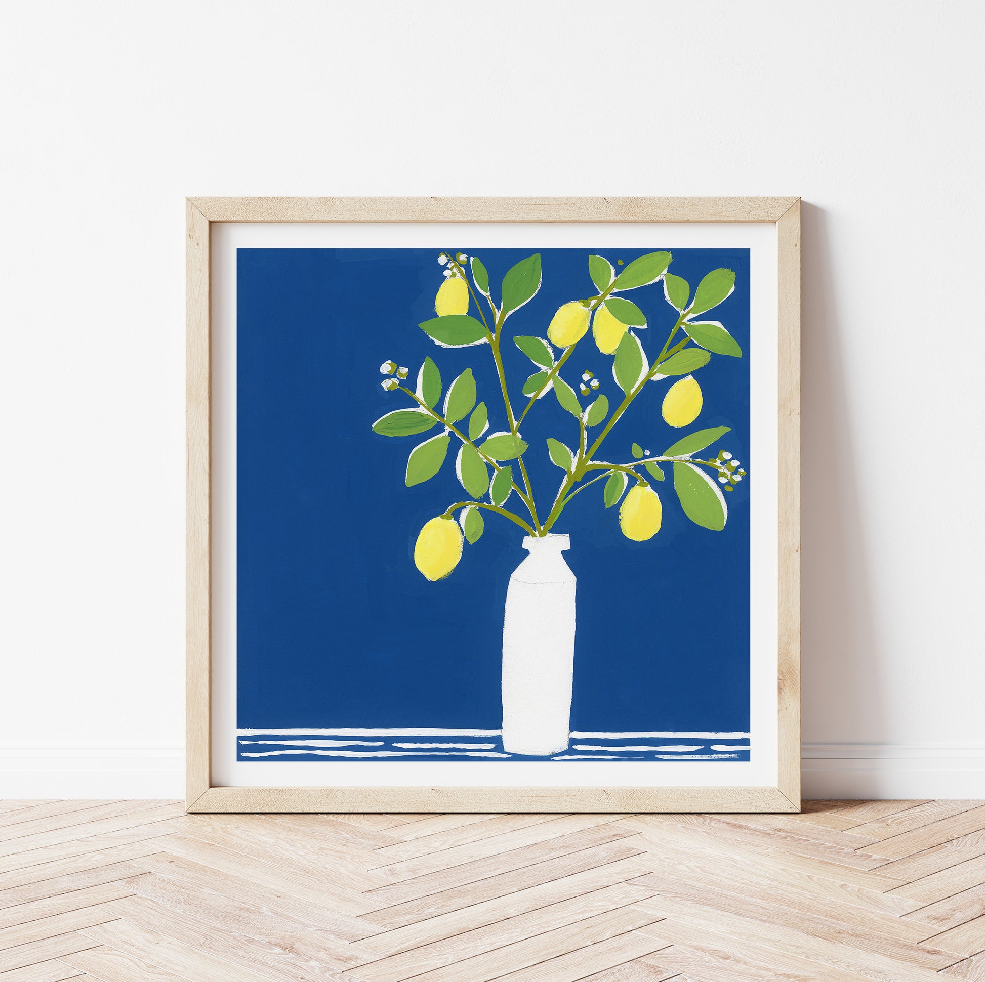 Framed artwork of a white vase with lemons on a blue background