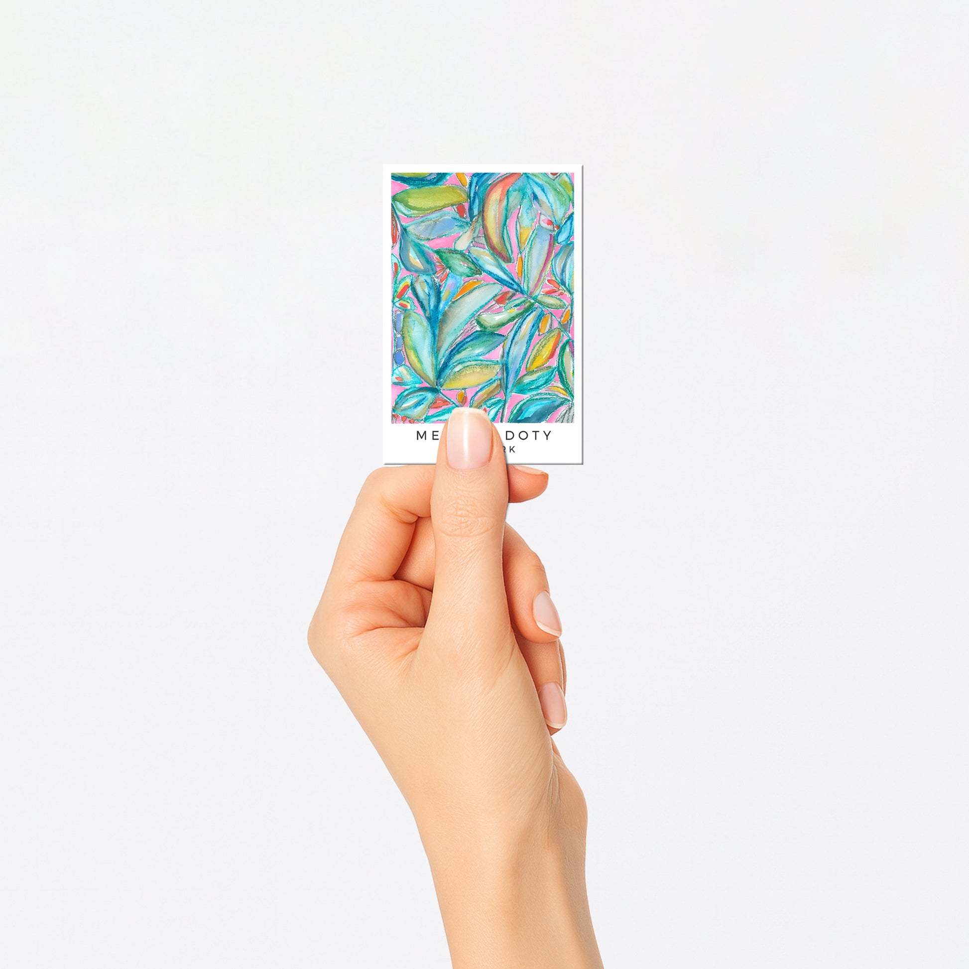 Hand holding a small card with colorful abstract design on a white background