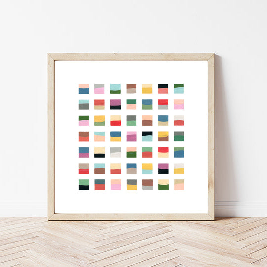 Framed artwork with a grid of colorful squares on a white wall.