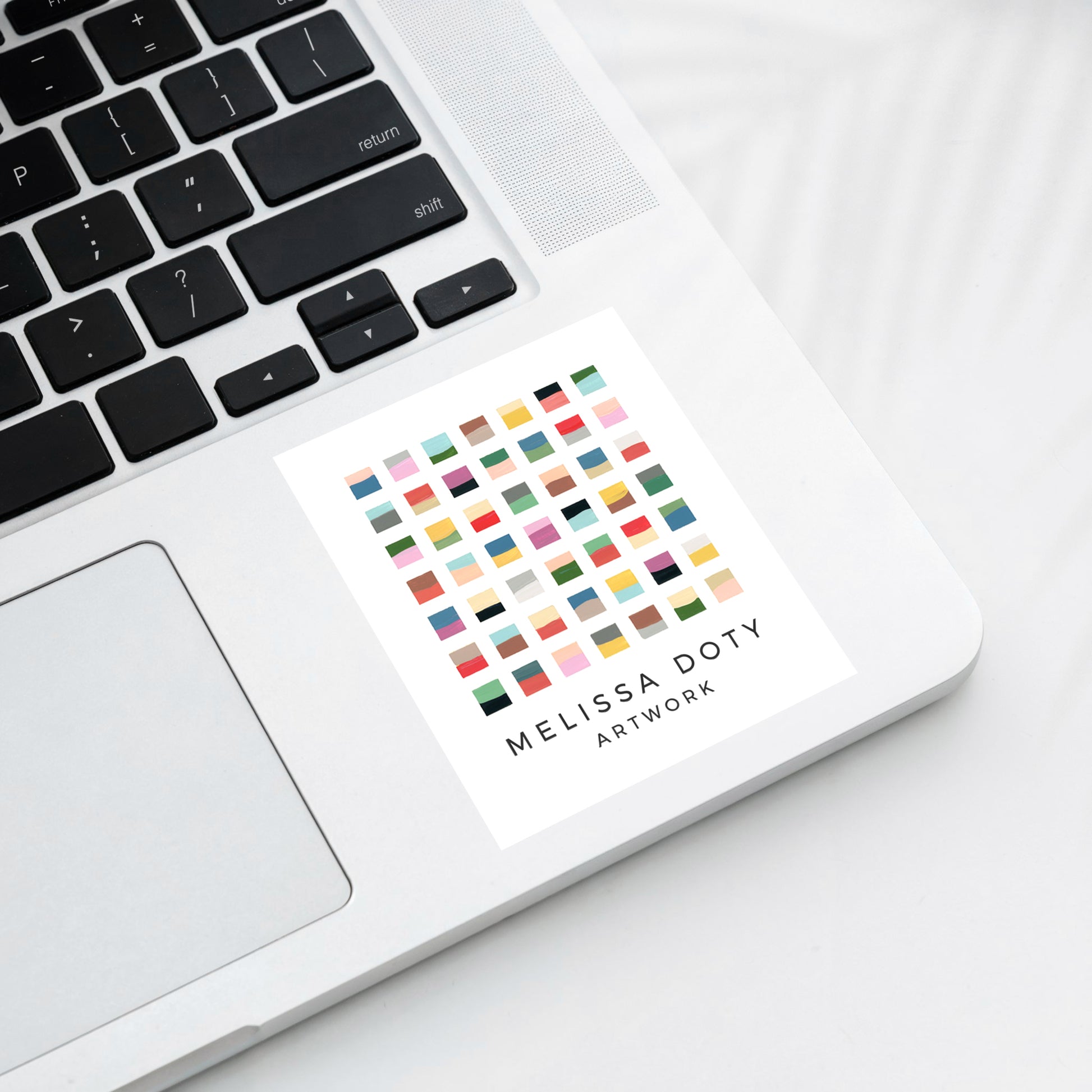 Color swatch grid with 'Melissa Doty Artwork' white vinyl sticker on laptop